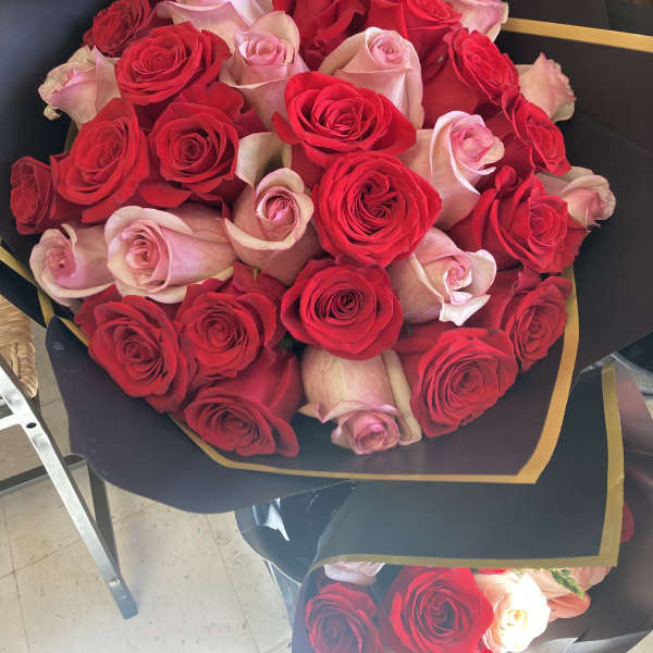 Bouquet of red and pale pink roses wrapped in black paper