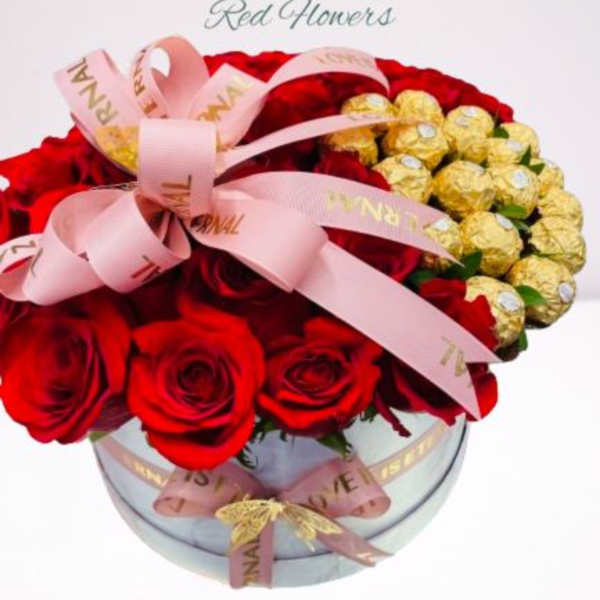 Red roses and gold-wrapped chocolates in a round glass box with pink ribbon
