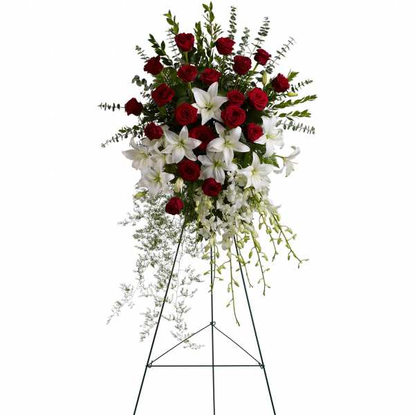 Standing floral spray with red roses and white lilies on a metal easel