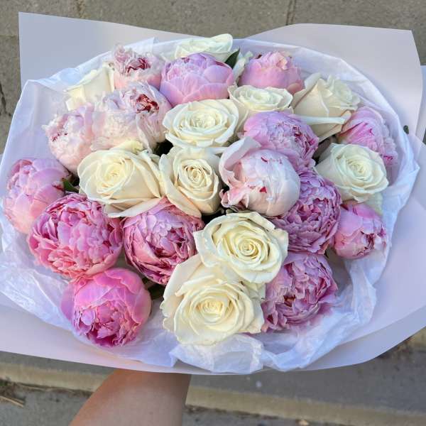 Bouquet of pink peonies and white roses wrapped in white paper