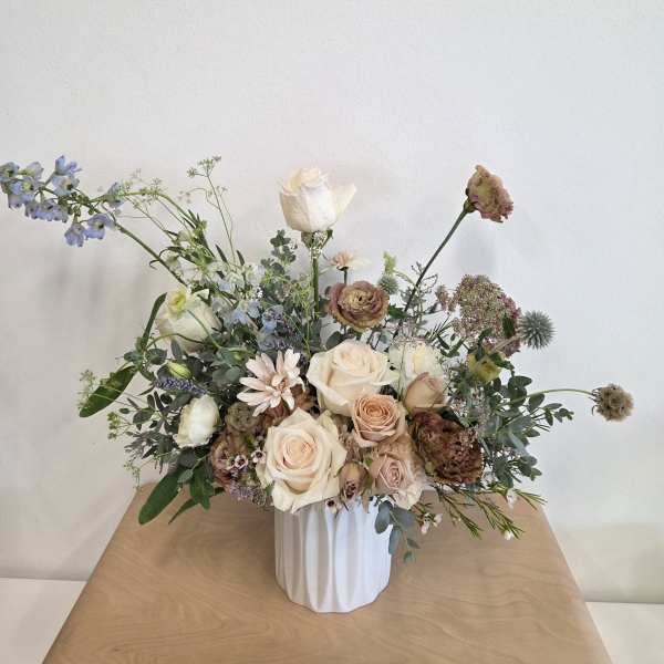 Loose bouquet of cream and blush roses in a white vase