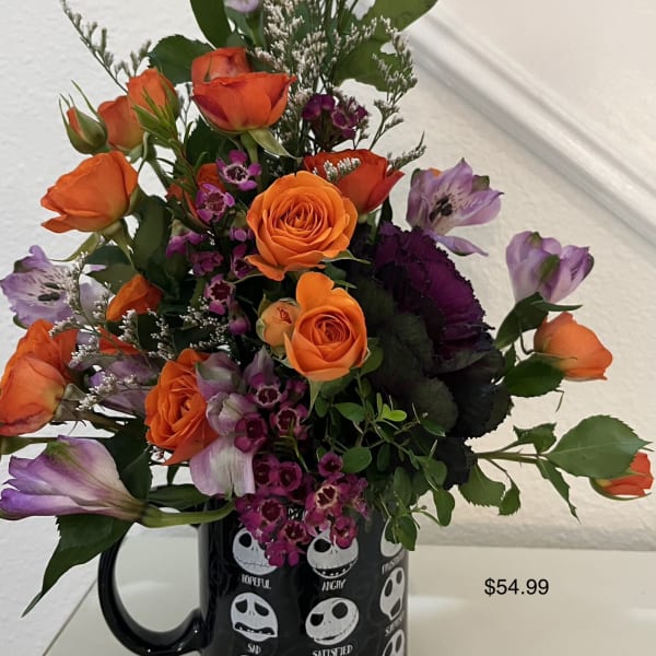 Orange roses and purple flowers arranged in a black mug-shaped vase
