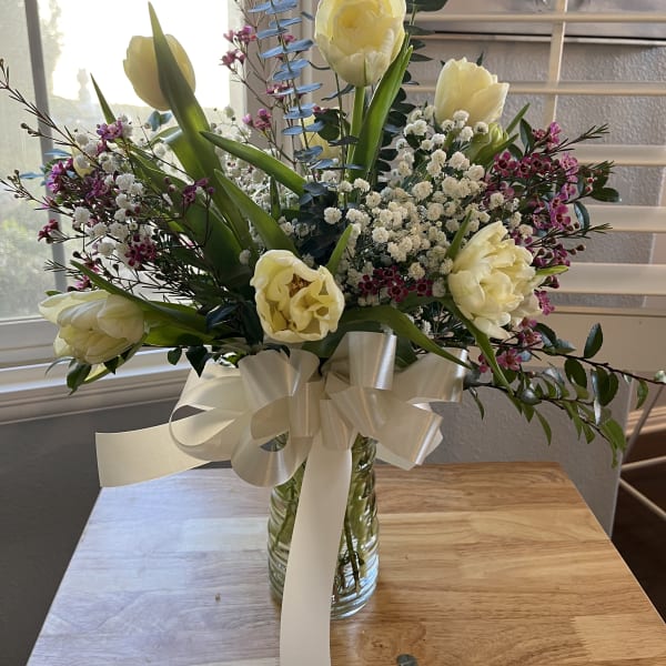 Bouquet of pale yellow tulips and small white flowers in a glass vase