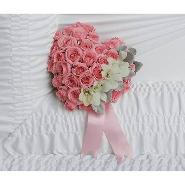 Pink rose bouquet with pale orchids and a pink ribbon on white bedding
