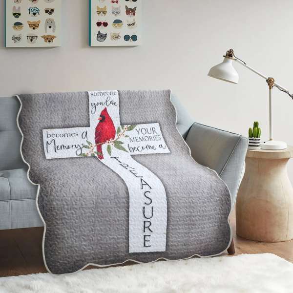 Gray quilted throw blanket with a cardinal and cross design on a sofa