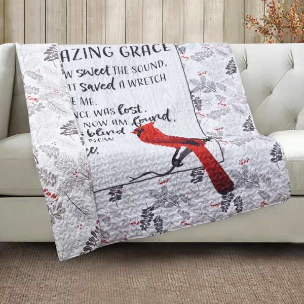 Quilted throw blanket with a red bird and printed text draped over a sofa