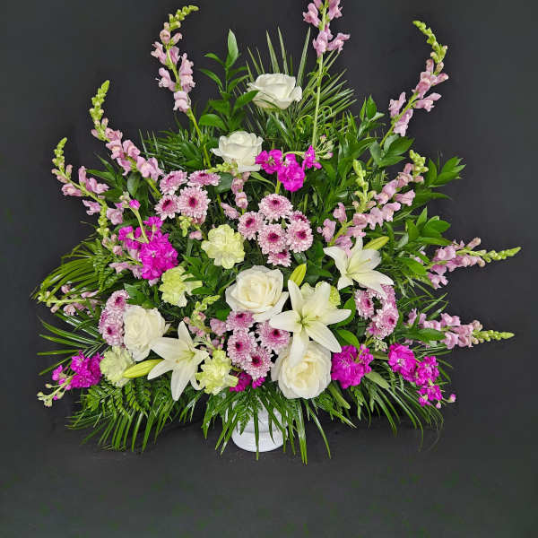 White lilies and roses with pink flowers in a white vase