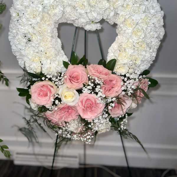 Heart-shaped white floral wreath with pink roses at the base