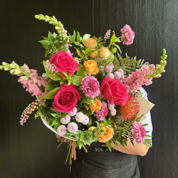 Handheld bouquet of pink, orange, and yellow flowers