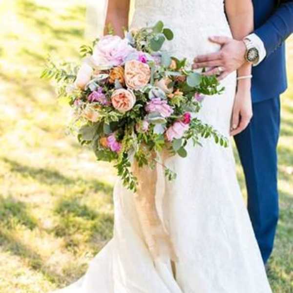 Bride holding a pastel bouquet with peach and pink roses