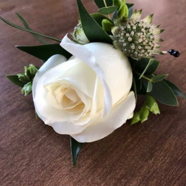 White rose boutonniere with green foliage and small filler flowers