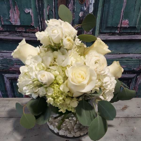 White roses and hydrangeas in a low glass vase with eucalyptus