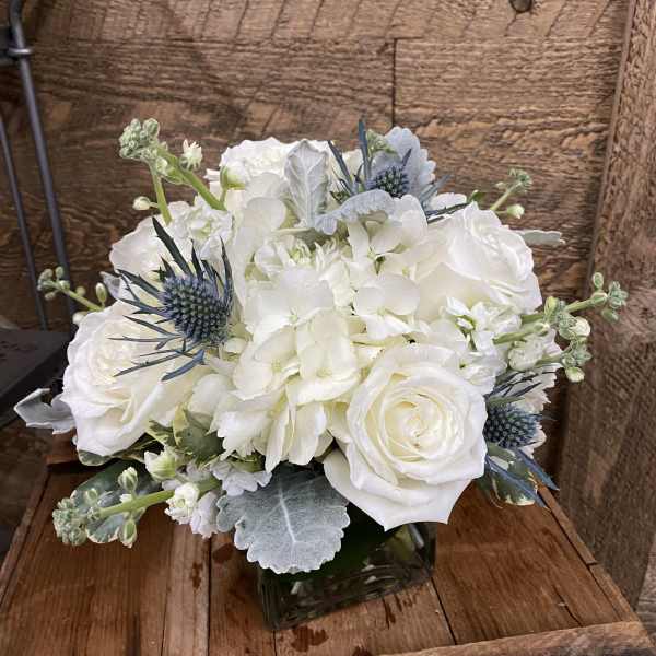 White roses and hydrangeas in a square glass vase