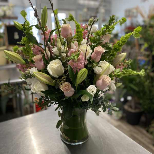 Pink and white rose bouquet with lilies in a glass vase