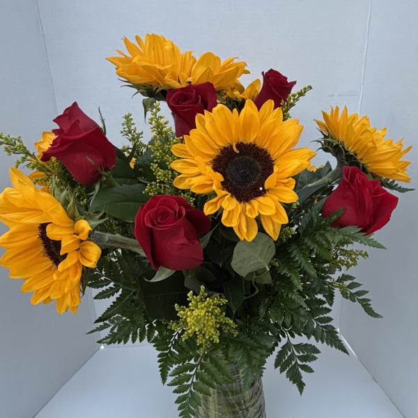Bouquet of red roses and yellow sunflowers in a glass vase