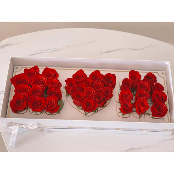 Three heart-shaped clusters of red roses in a white gift box