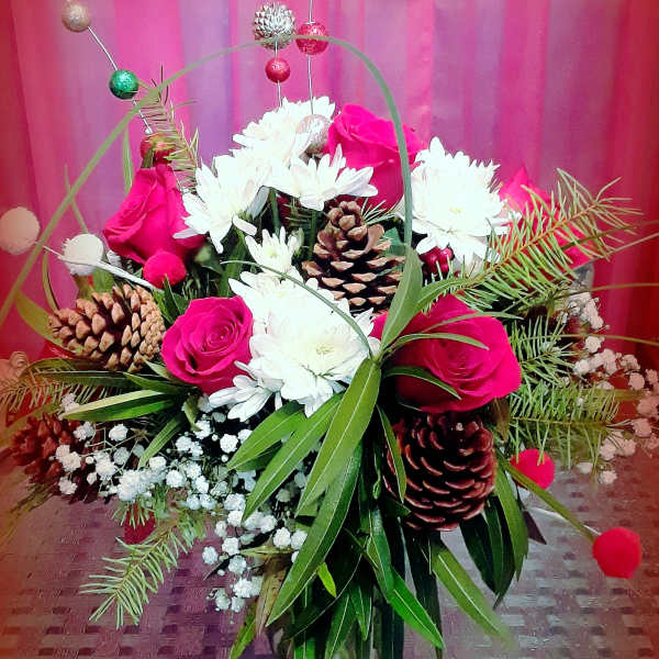 Pink roses and white daisies arranged with pinecones in a decorative basket.