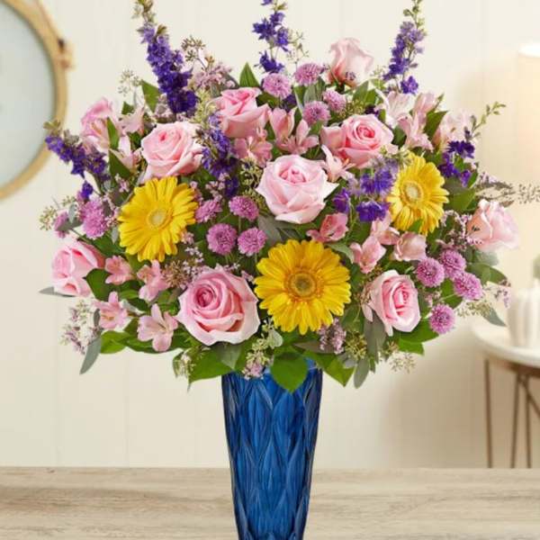 Pink roses and yellow daisies in a blue vase