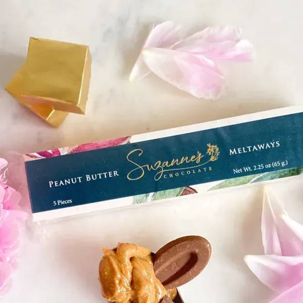 Box of peanut butter meltaway chocolates with pink flower petals and gold foil accents