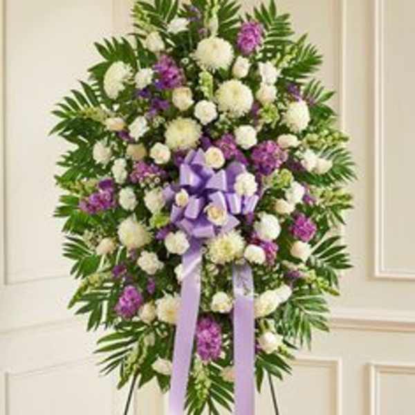 Standing funeral wreath of white and purple flowers with a lavender ribbon