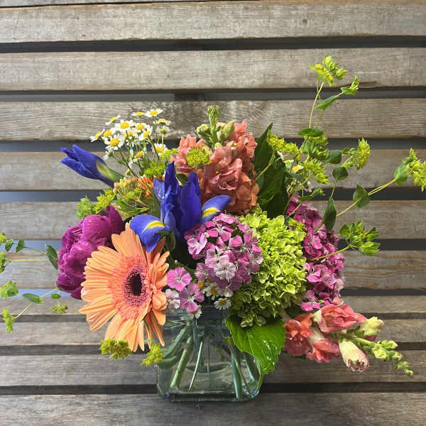 Colorful mixed bouquet in a clear glass vase with gerbera, iris, and hydrangea