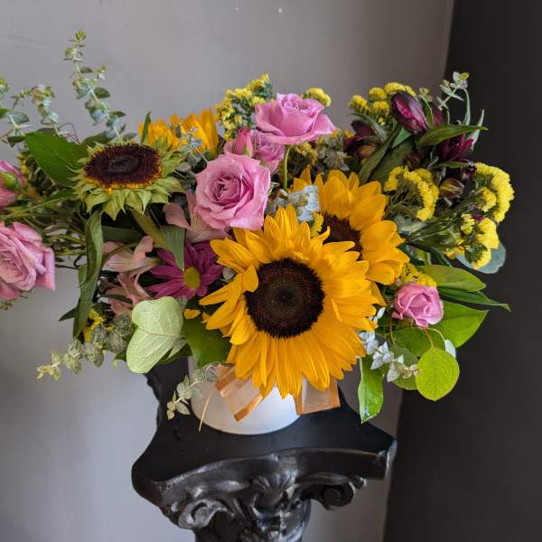 Bouquet of sunflowers and pink roses in a white vase