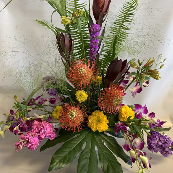 Tall tropical bouquet with purple orchids and orange pincushion blooms