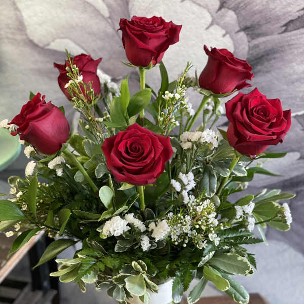 Red roses arranged in a clear glass vase with white filler flowers