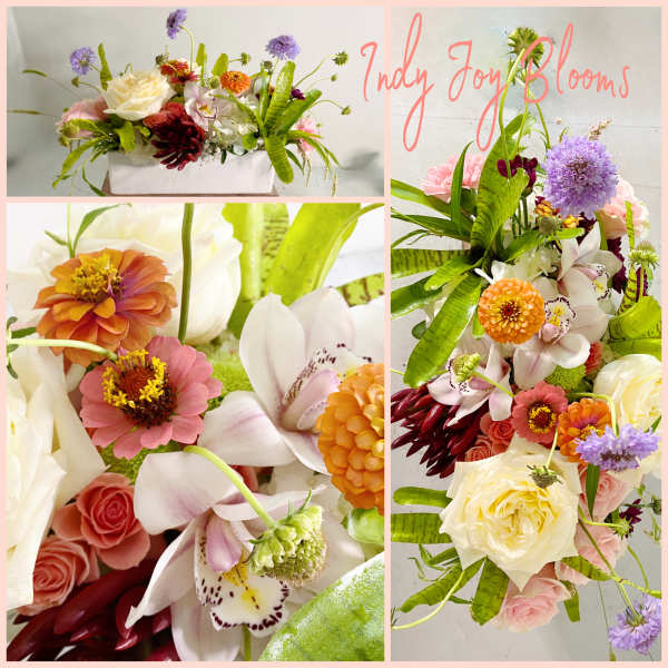 Mixed bouquet with roses, orchids, and zinnias in a white rectangular vase