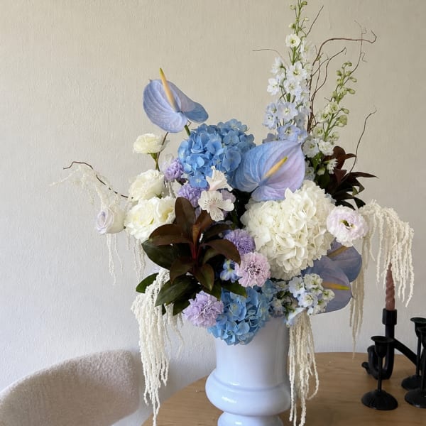 Large pastel floral arrangement in a white vase on a table