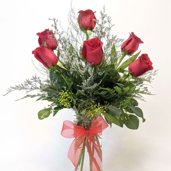 Red roses in a clear glass vase with a red ribbon