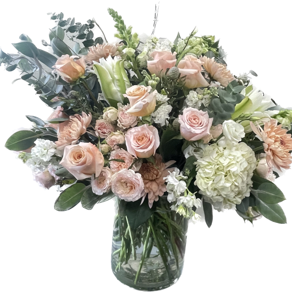 Blush roses and pale flowers in a clear glass vase