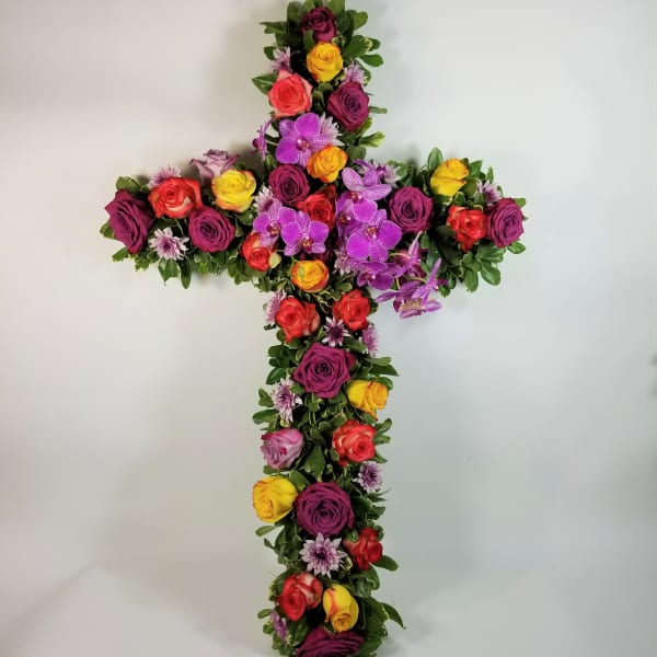 Cross-shaped floral arrangement with multicolored roses and purple orchids