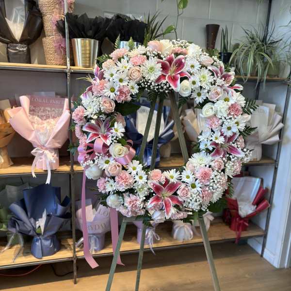 Heart-shaped floral wreath on an easel with pink and white flowers