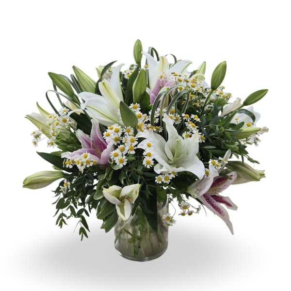 Bouquet of white and pink lilies with small white daisies in a glass vase
