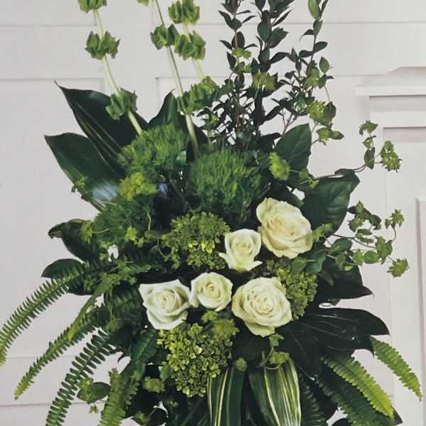 Tall white rose arrangement with lush green foliage on a stand