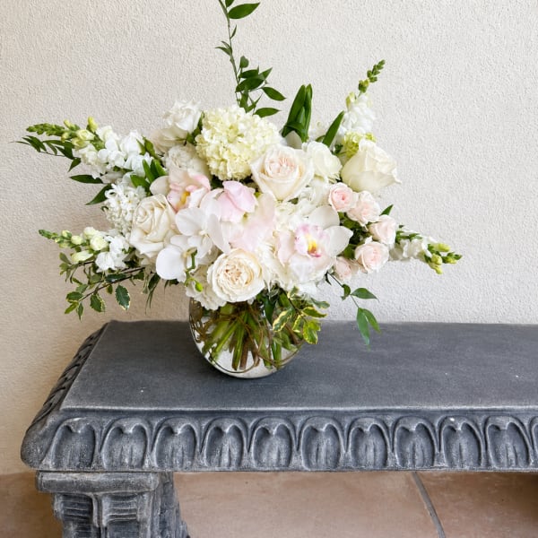 White and blush floral arrangement in a round glass vase