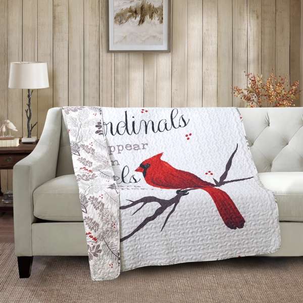 Quilted throw blanket with a red cardinal design draped over a sofa