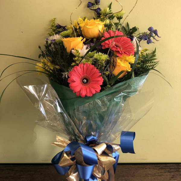 Mixed bouquet with yellow roses and pink gerbera daisies in clear wrap
