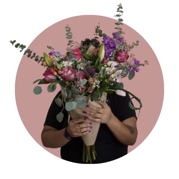 Large bouquet of pink, purple, and white flowers wrapped in paper