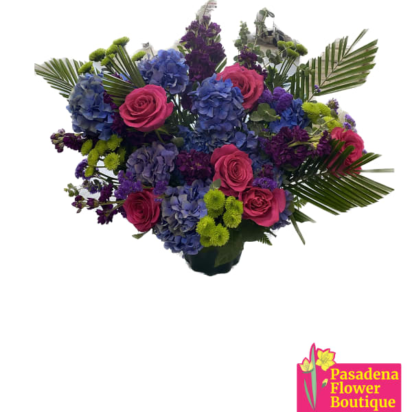 Bouquet of pink roses, blue hydrangeas, and purple flowers with palm fronds