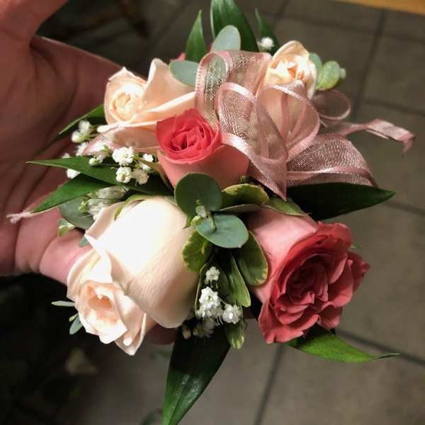 Small hand-tied bouquet of pink and cream roses with ribbon