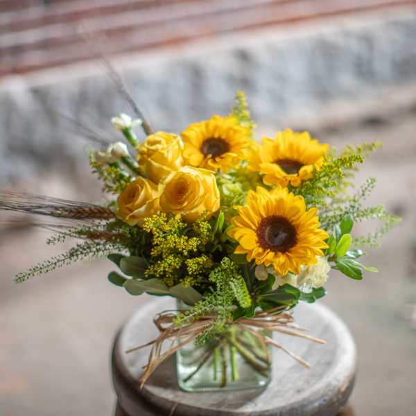 Yellow sunflowers and roses in a square glass vase
