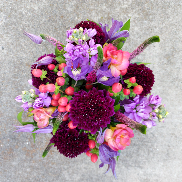 Bouquet of purple, pink, and coral flowers with berry accents