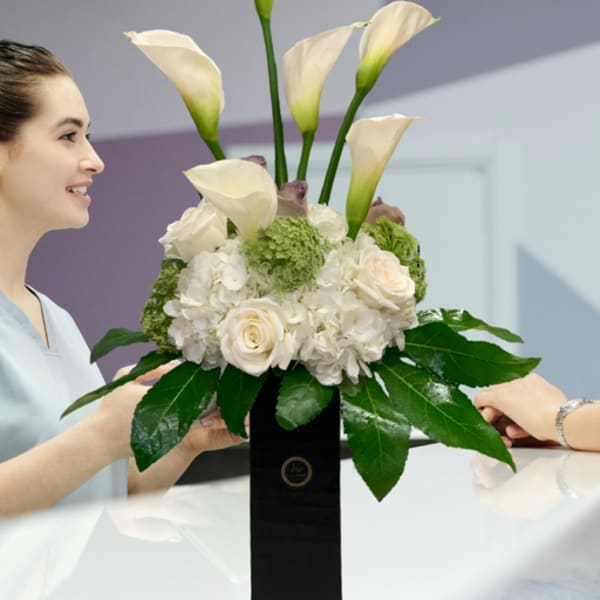 White calla lilies and roses arranged in a black vase
