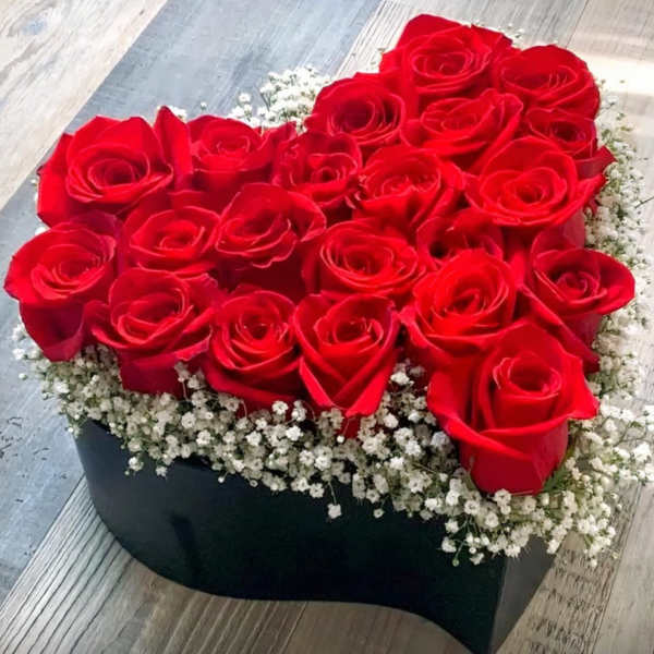 Heart-shaped box filled with red roses and white baby's breath