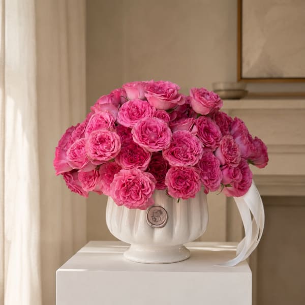 Pink rose bouquet in a white vase with a ribbon