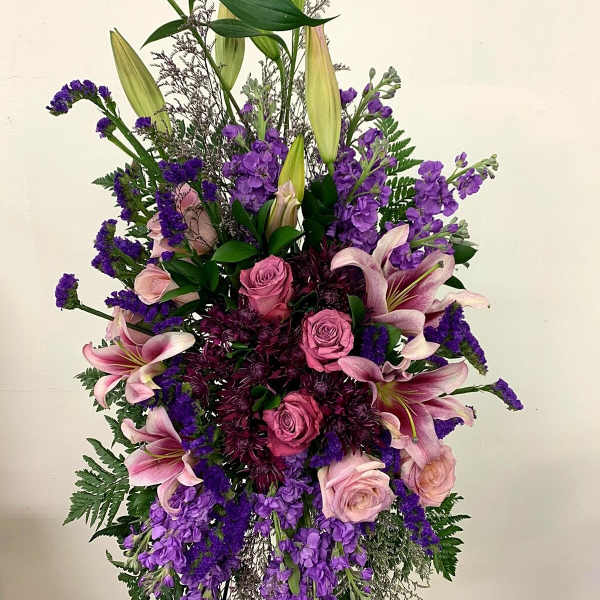 Tall standing arrangement of pink and purple flowers with lilies and roses