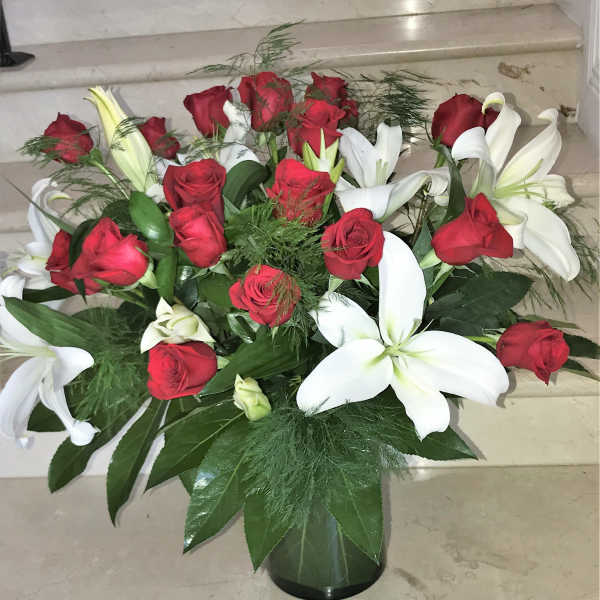 Arrangement of red roses and white lilies in a dark glass vase