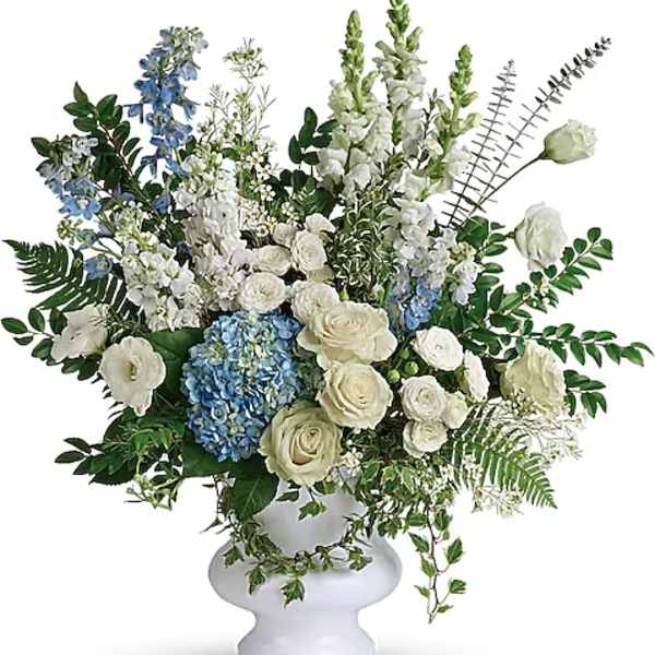 White and blue floral arrangement in a white pedestal vase